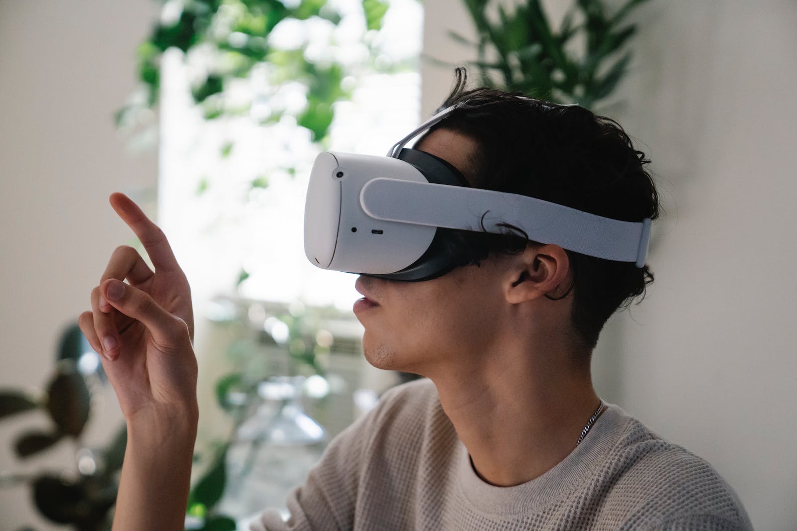 Side view of concentrated young guy in casual clothes experiencing virtual reality in modern headset at home