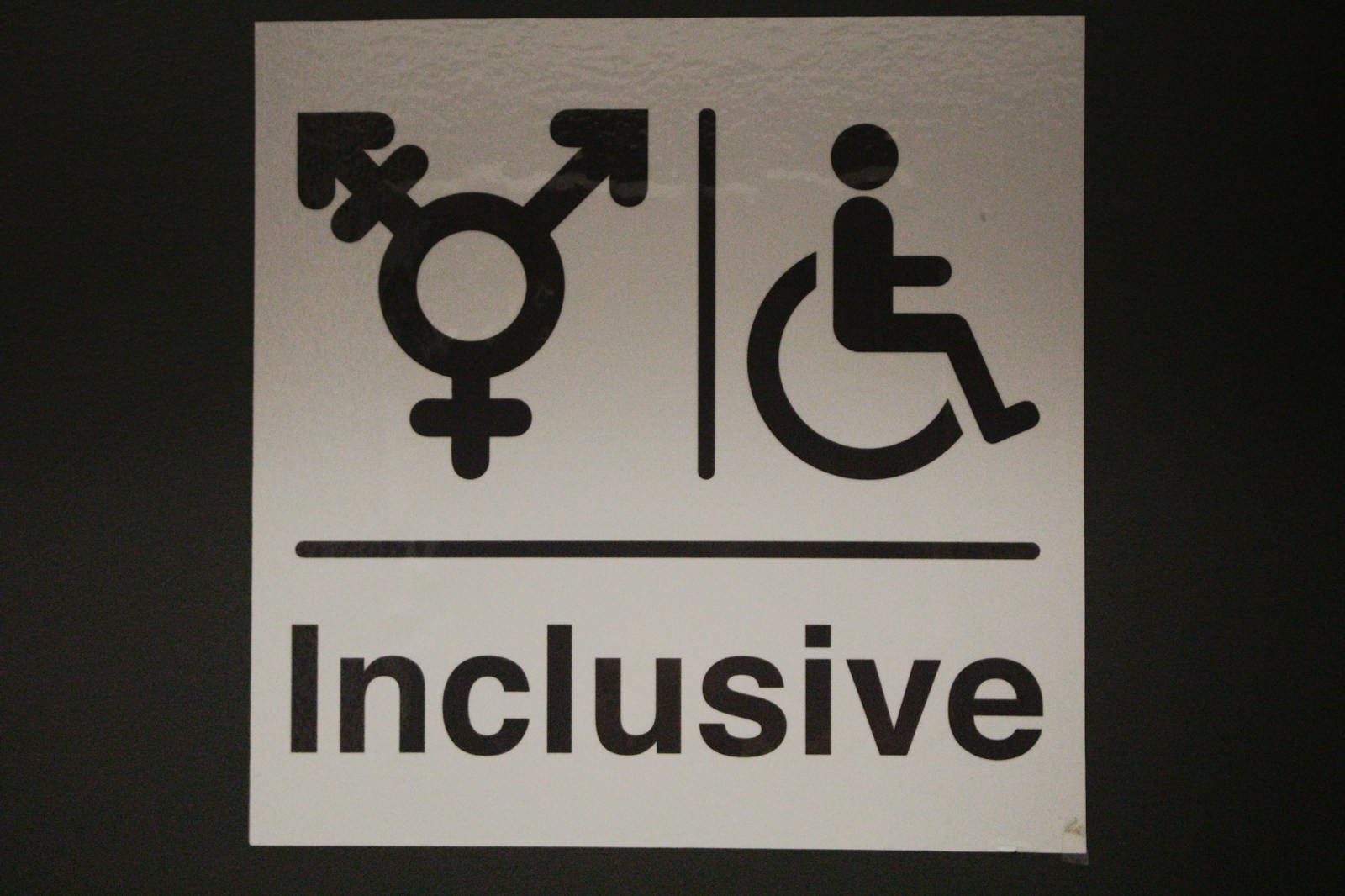 A white sign with a black and white image of a person in a wheelchair